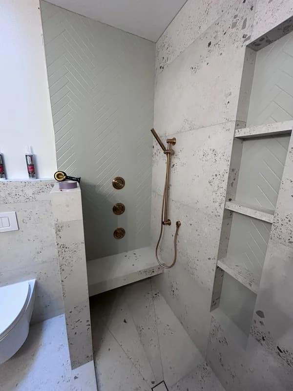 Master bathroom in London Ontario with large-format and herringbone tile, bench, niche